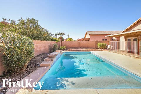 A swimming pool in a backyard with a house in the background.