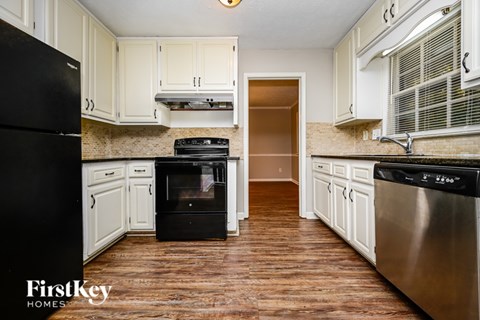 A kitchen with wooden floors and white cabinets.