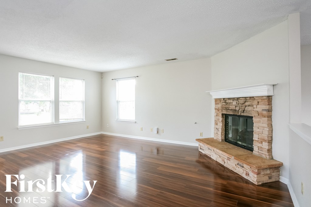 A spacious living room with a fireplace and wooden floors.