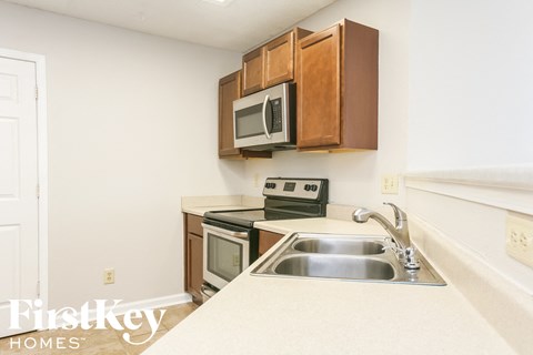 A kitchen with a stove, microwave, and sink.