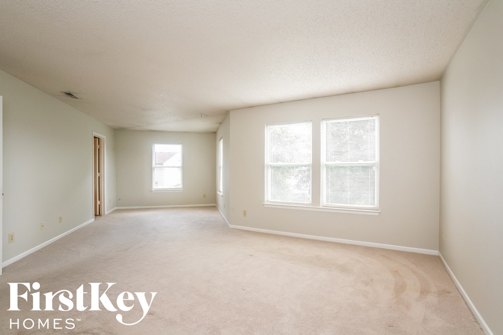 A spacious empty room with a window and a door.