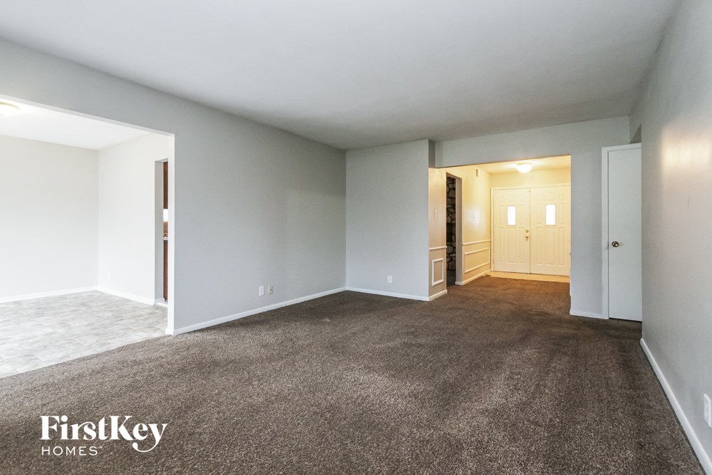 an empty living room with carpet and white walls