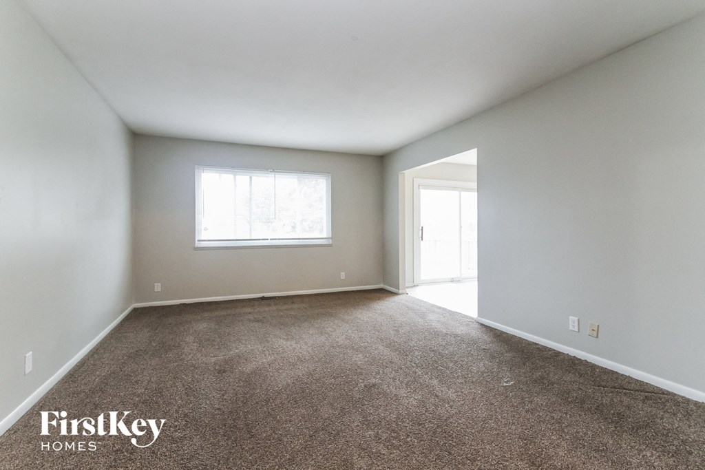 an empty living room with carpet and a window