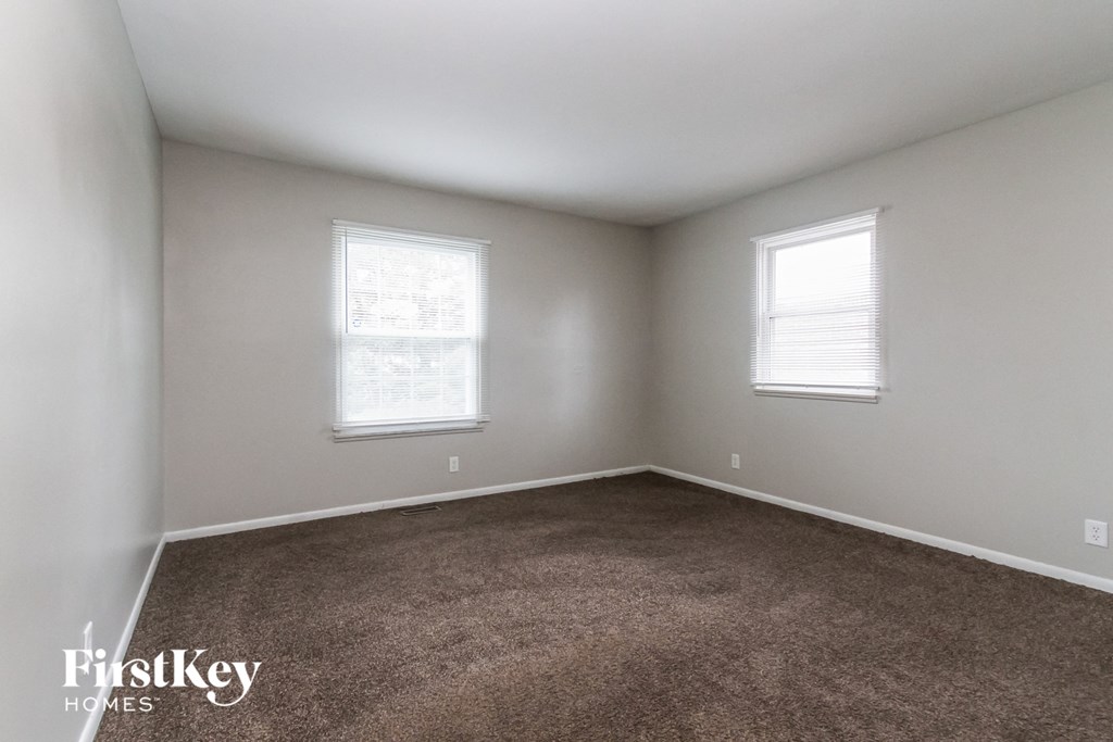 a bedroom with a carpeted floor and two windows