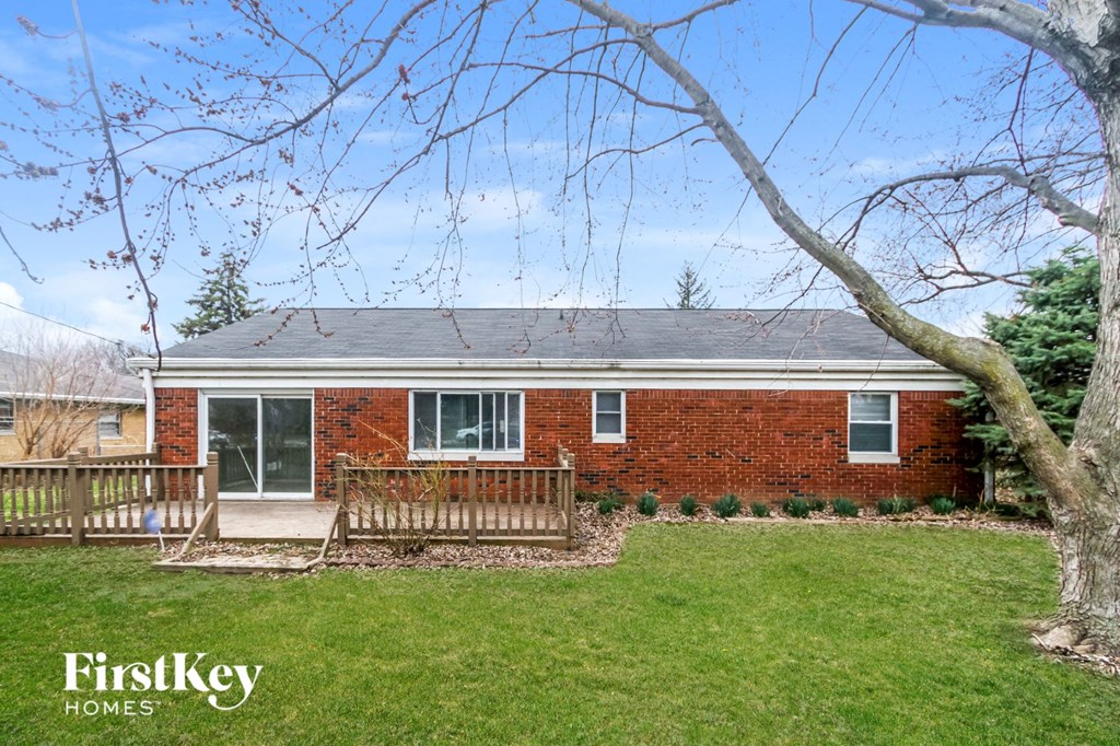 a small brick house with a yard and a deck