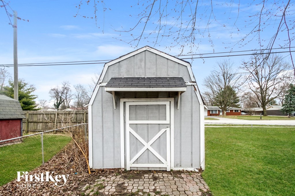 a small gray shed with a white door