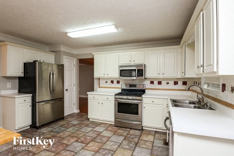 A kitchen with white cabinets and a tile floor.