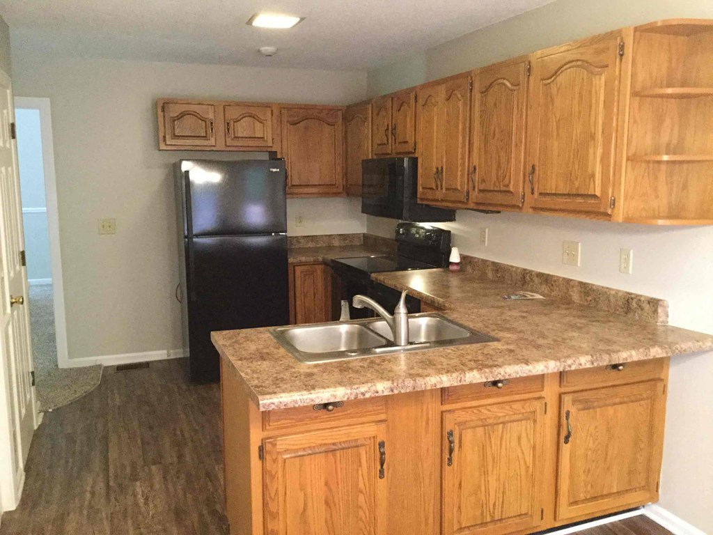 a kitchen with wooden cabinets and a black refrigerator