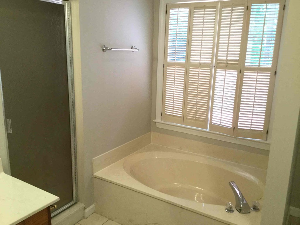 a bathroom with a tub and a shower and a window