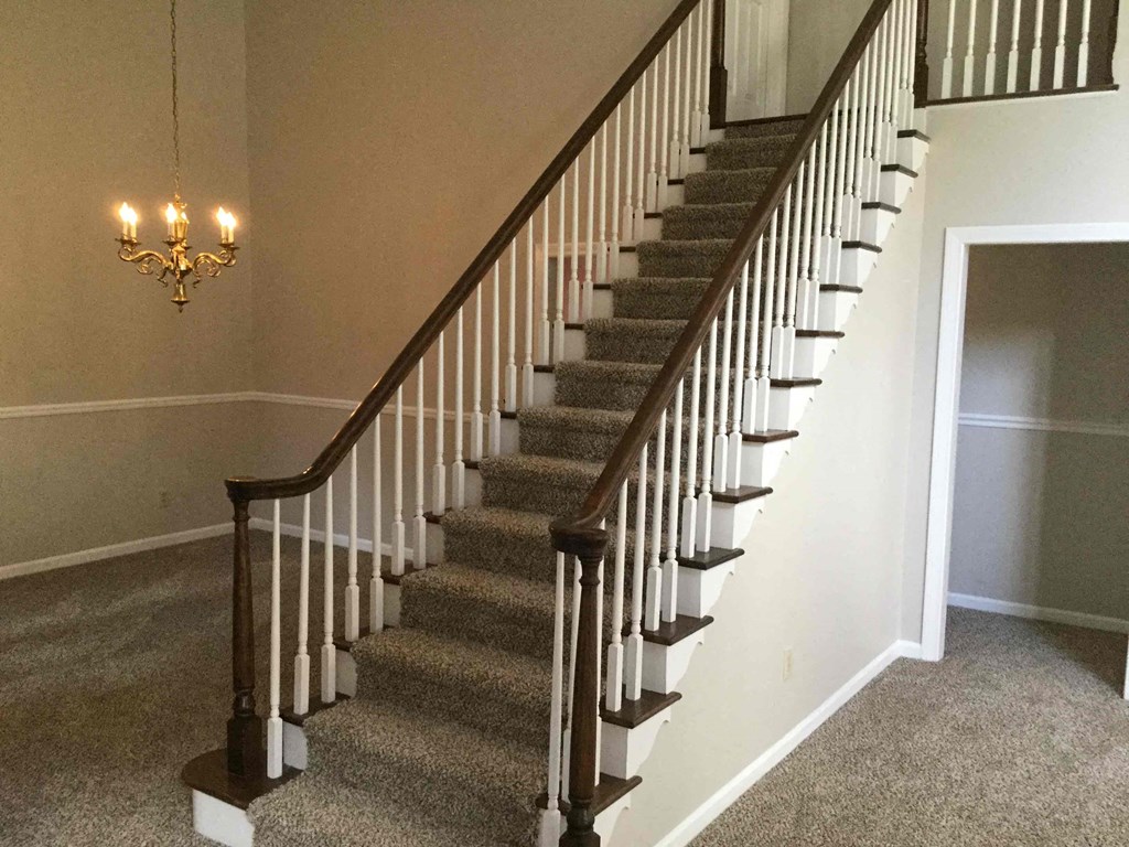 a set of stairs with carpeting and a chandelier