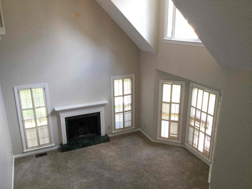 an empty living room with a fireplace and windows