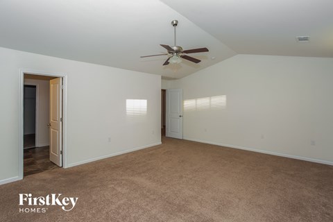 A spacious room with a ceiling fan and carpeted floor.