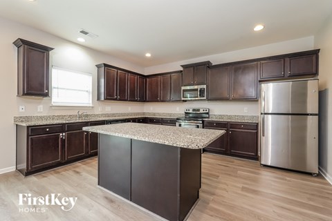 A kitchen with dark brown cabinets and a granite countertop.