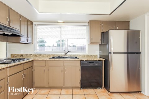 A kitchen with a stainless steel refrigerator and a black trash can.