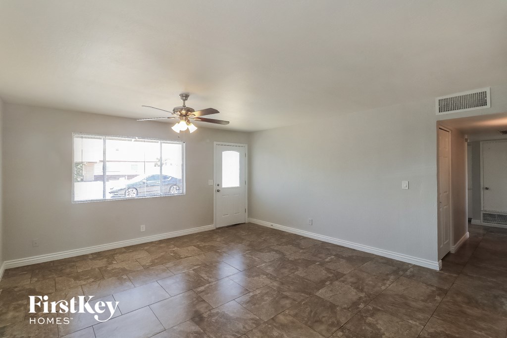 an empty living room with a ceiling fan and a window