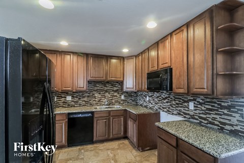 a kitchen with wood cabinets and granite counter tops and black appliances