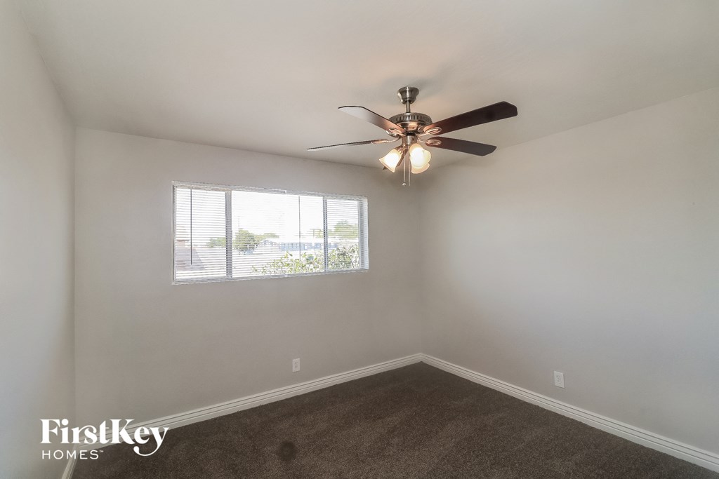 an empty bedroom with a ceiling fan and a window