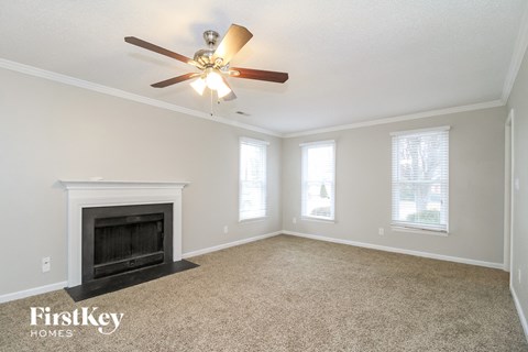A spacious room with a fireplace and a ceiling fan.