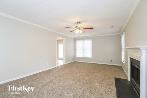 A spacious room with a fireplace and a ceiling fan.