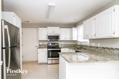 A kitchen with granite countertops and white cabinets.