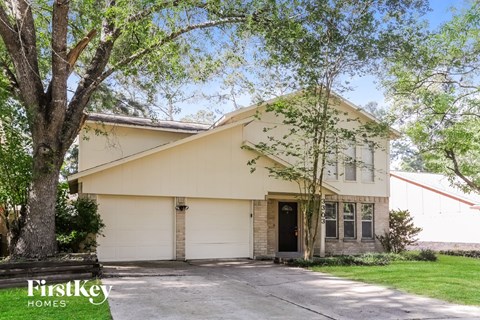 a house with a driveway and trees in front of it