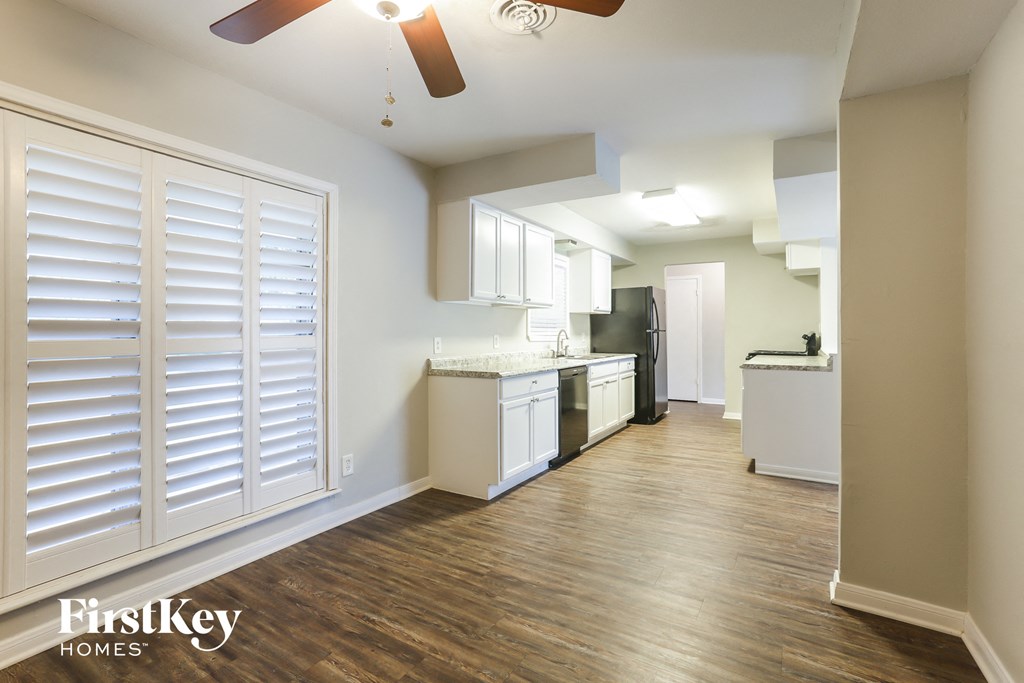 a kitchen and living room with white shutters and a wood floor