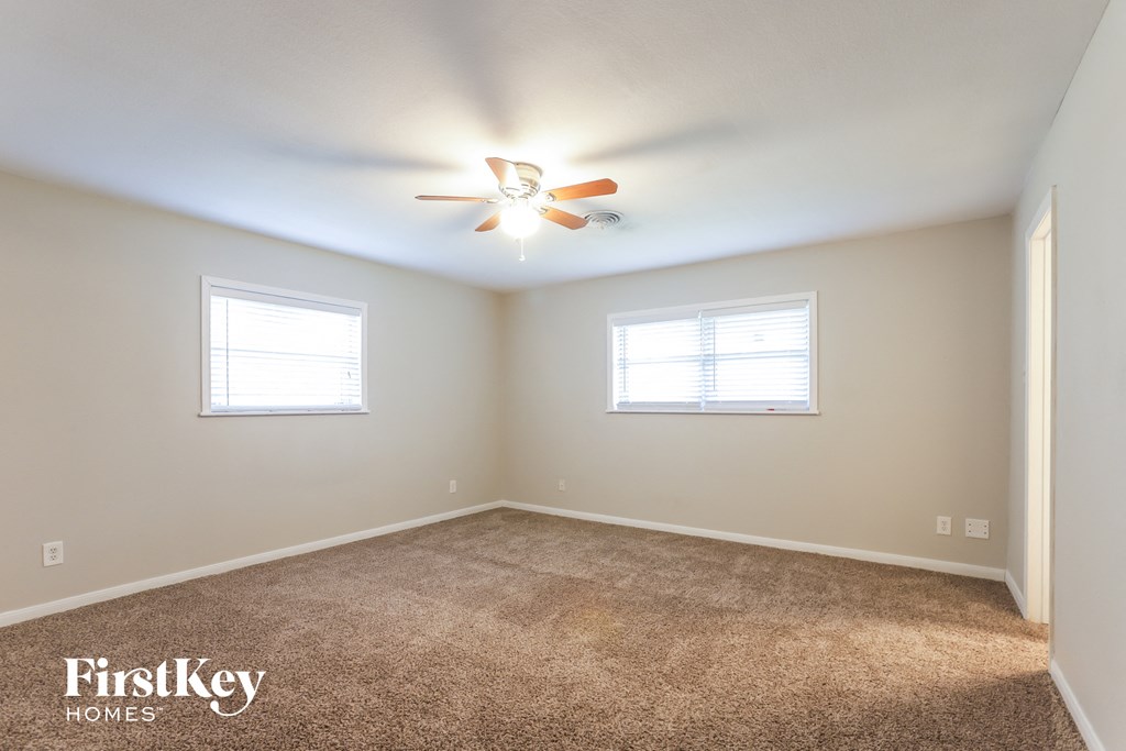an empty room with a ceiling fan and two windows