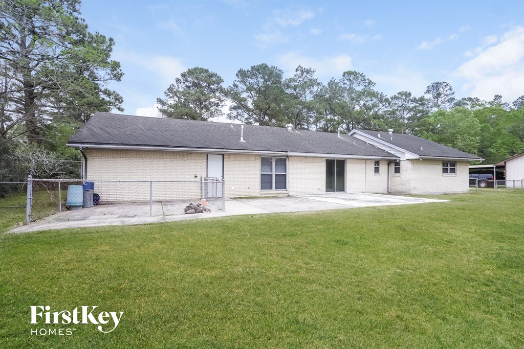 a white brick house with a yard and a chain link fence