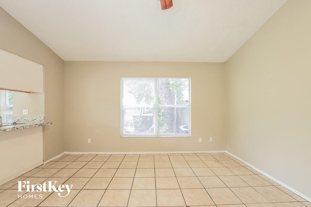 an empty living room with a window and a tiled floor