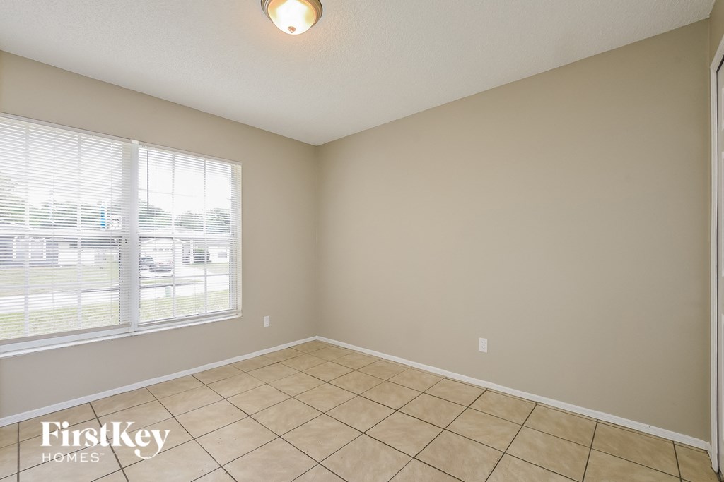 the living room of an empty home with tiled floors and a large window