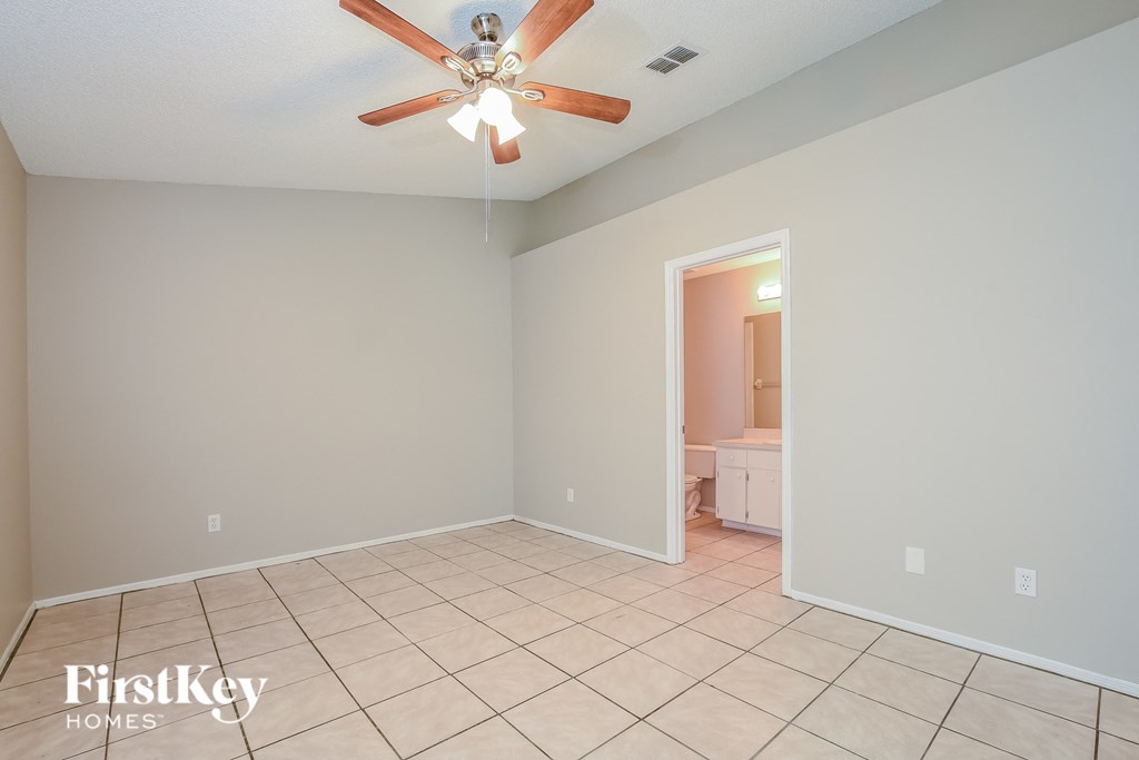 a empty living room with a ceiling fan and a tiled floor