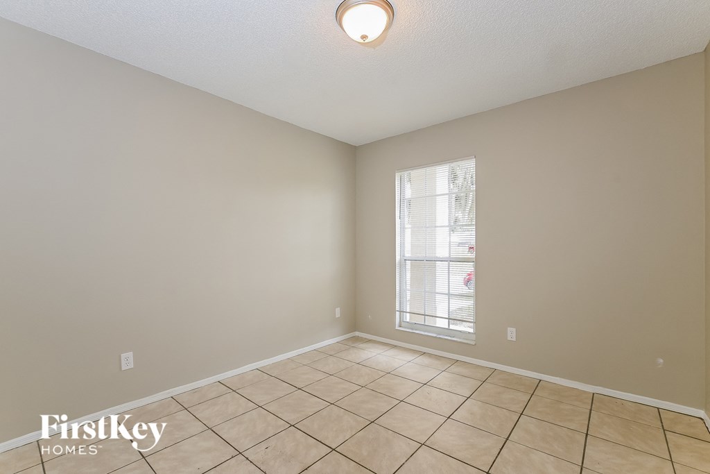 the living room of an empty home with tile floors and a window
