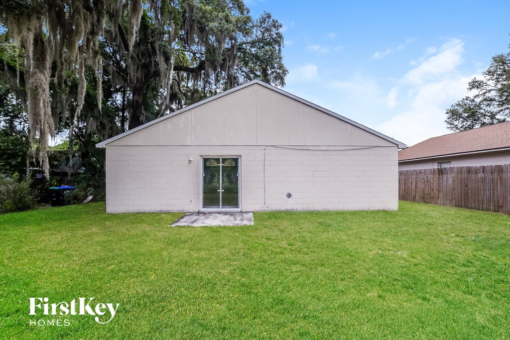 the backyard of a white house with a lawn and a tree