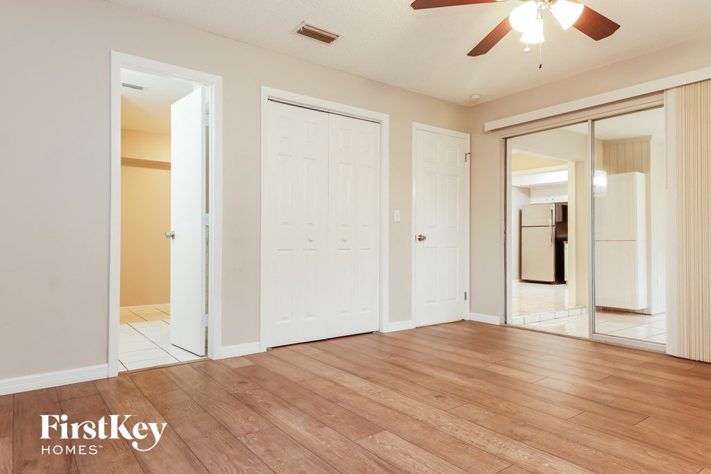 A spacious room with wooden floors and a ceiling fan.