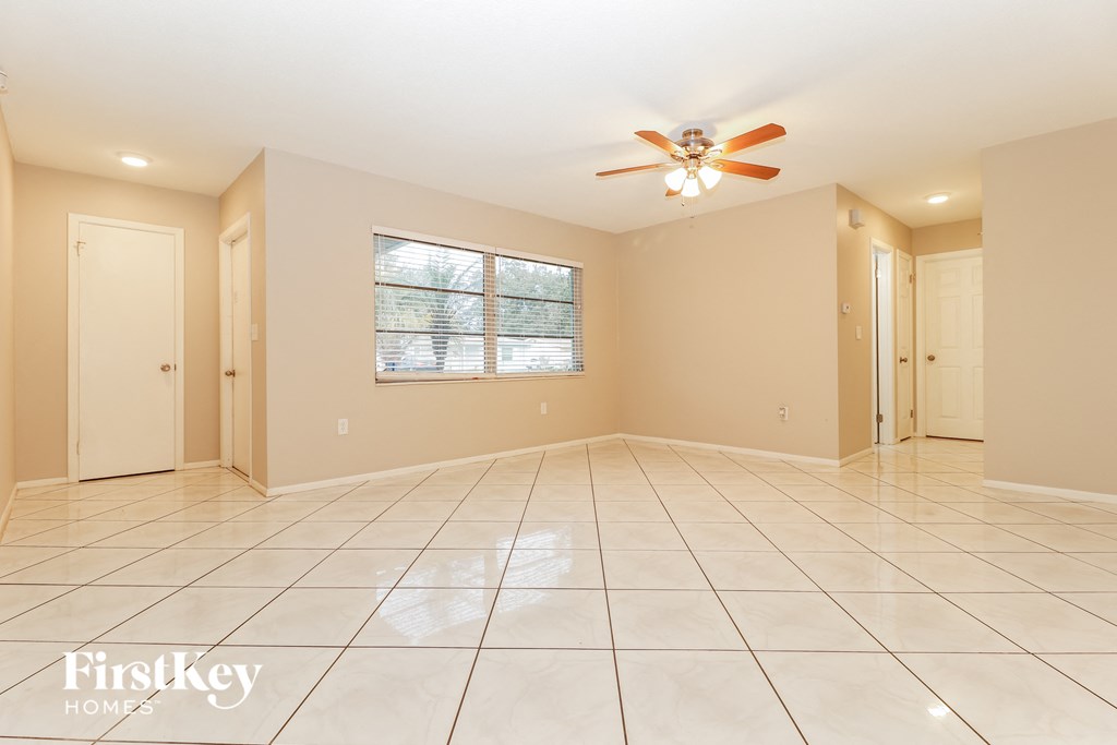 A spacious room with a ceiling fan and tiled flooring.