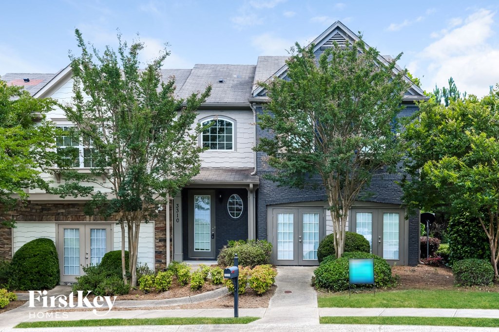 the front of a house with trees and a blue mailbox