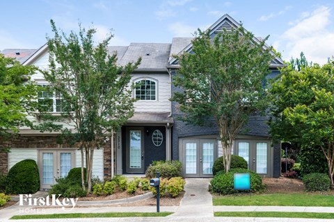 the front of a house with trees and a blue mailbox