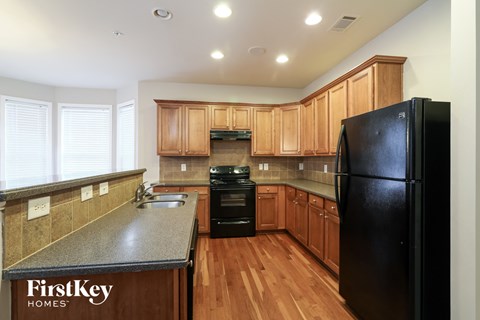 a kitchen with wooden cabinets and a black refrigerator