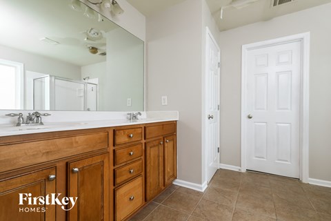 the master bathroom has a large vanity with two sinks and a large mirror