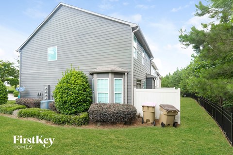 a house with a fence and a yard with trash cans