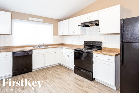 A kitchen with black appliances and white cabinets.
