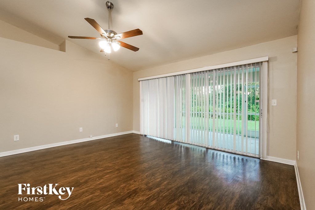 the living room of an empty house with a large window and a ceiling fan