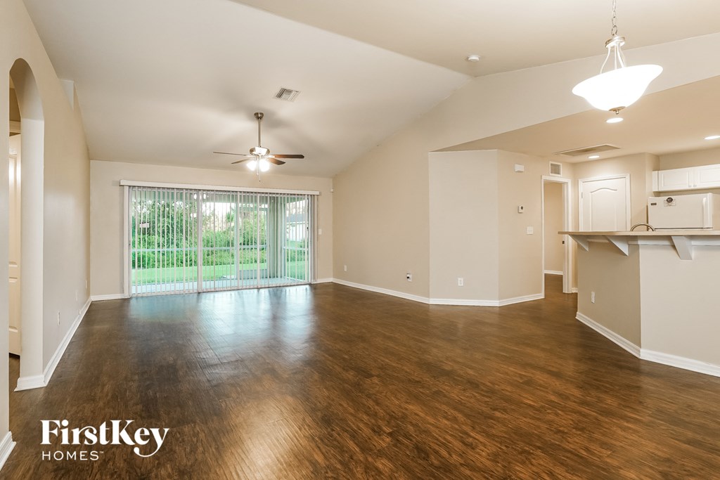 an empty living room and kitchen with wood flooring and a large window