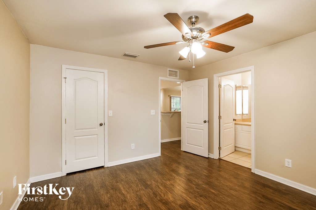 a living room with a ceiling fan and a door to a bathroom