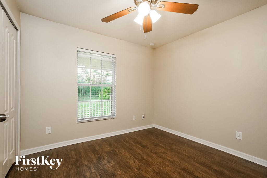 the living room of an empty home with wood flooring and a ceiling fan