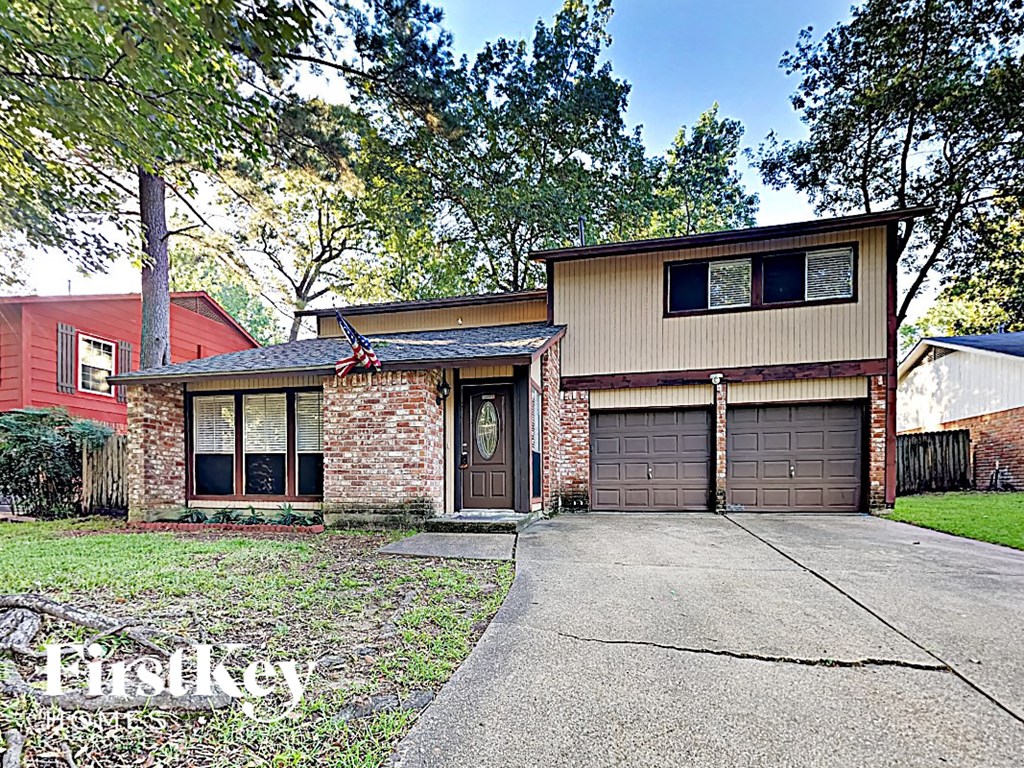 a brick house with two garage doors and a driveway