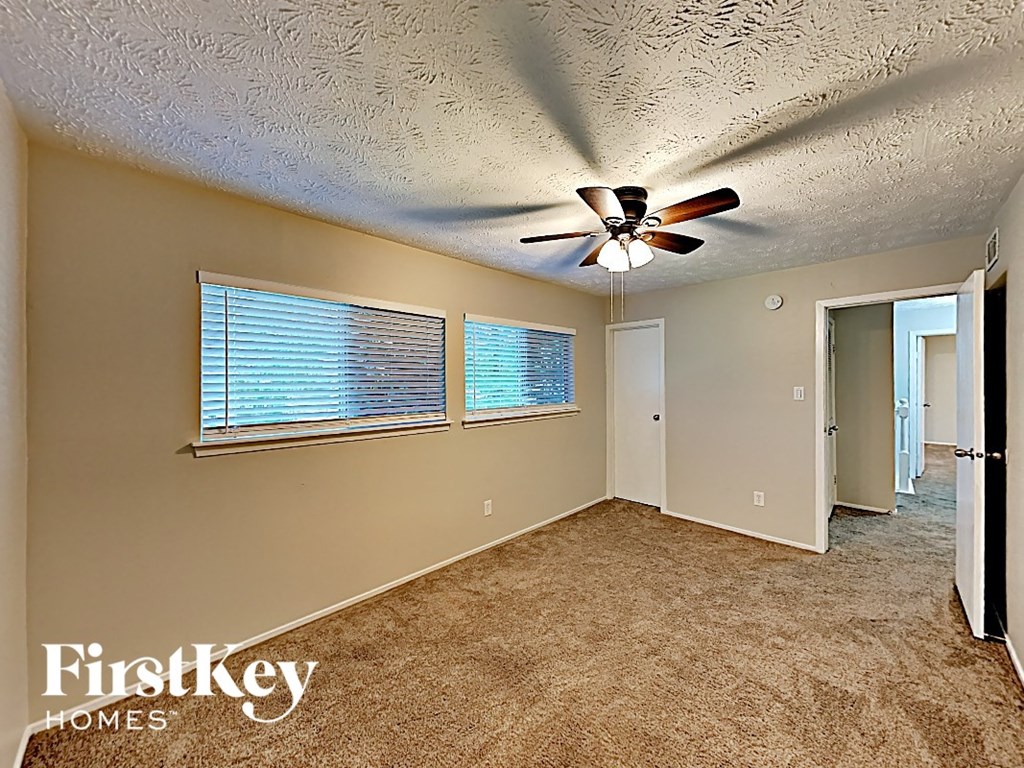 an empty living room with a ceiling fan and a window