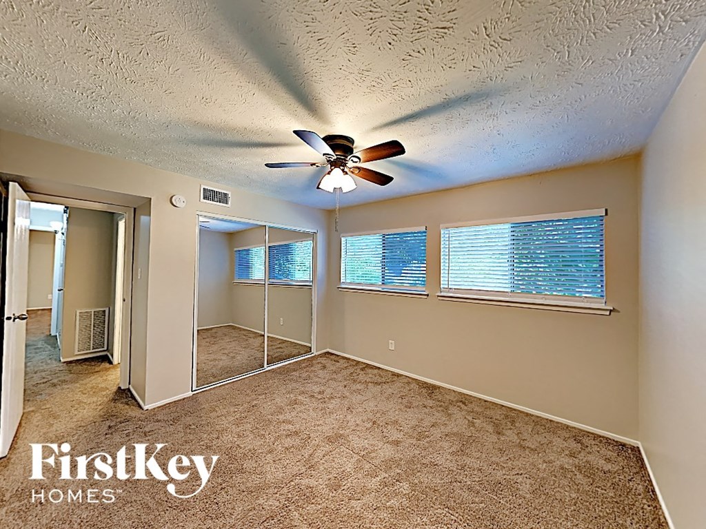 an empty living room with a ceiling fan and a large window
