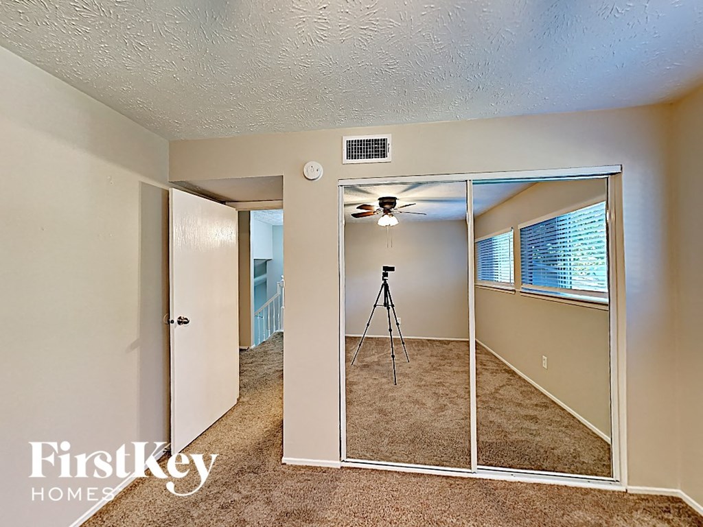 an empty bedroom with mirrored closet doors and a ceiling fan