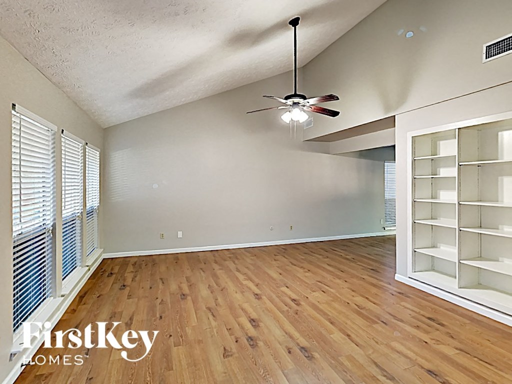 an empty living room with wood floors and a ceiling fan
